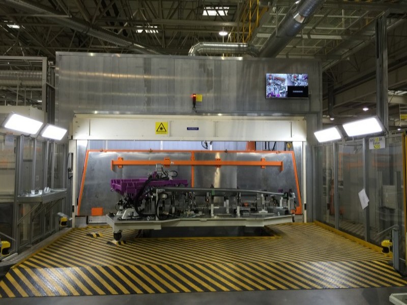 Detailed view of an integrated robotic welding cell ensuring consistent weld quality in car manufacturing.